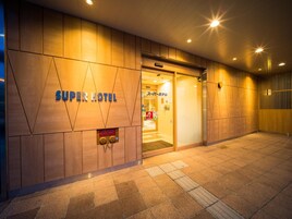 A hotel entrance with a modern design, featuring a prominent 'Super Hotel' sign.