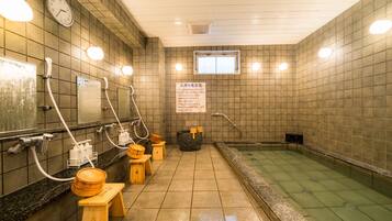 Relax in a serene onsen bath area with a spacious soaking area, wooden bench, and multiple bathing options.