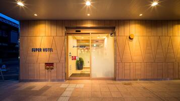 The exterior of a hotel with a modern design, featuring a prominent entrance and a sign that reads "Super Hotel".