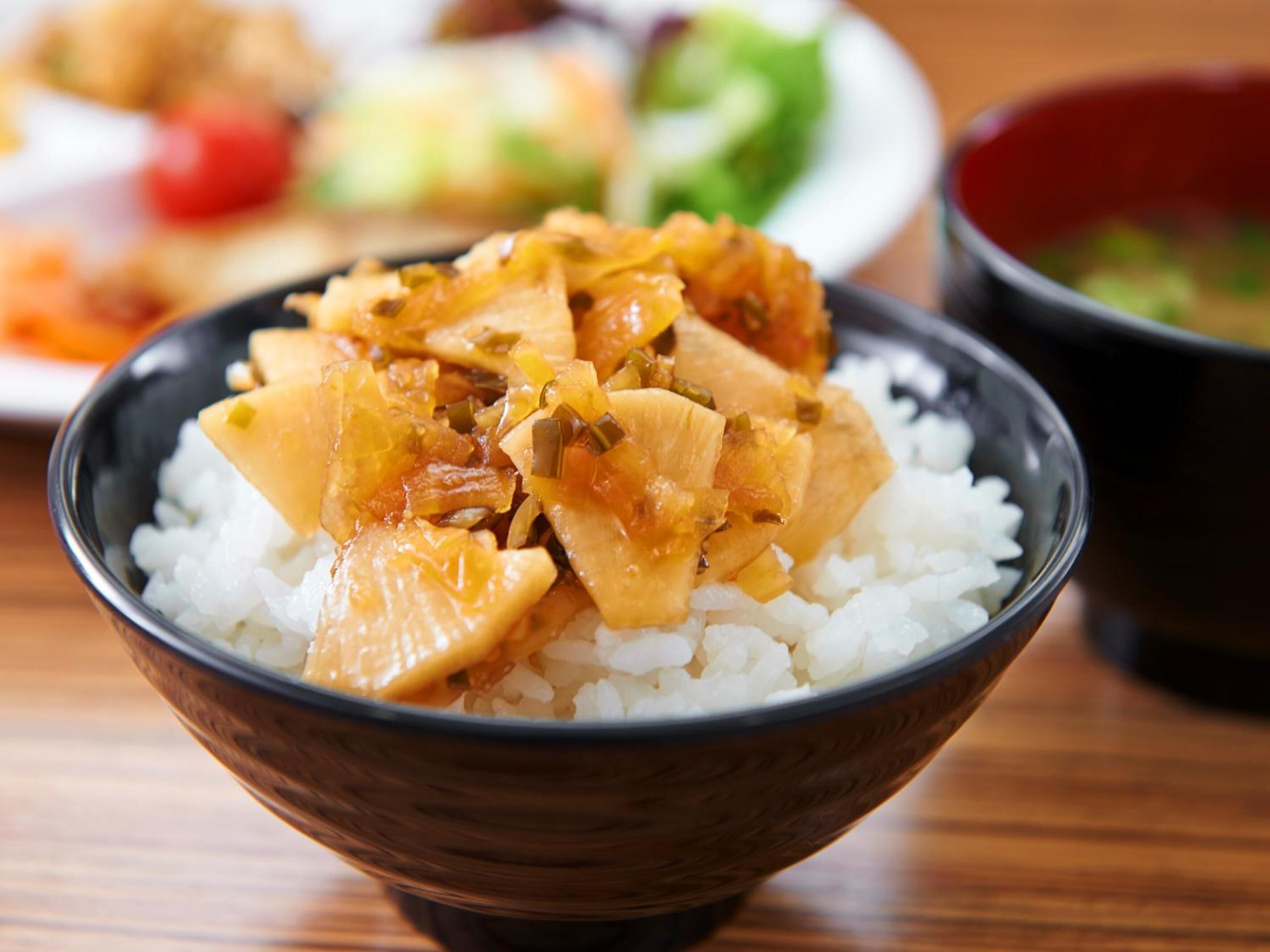 A bowl of rice topped with a dish of chicken and vegetables.