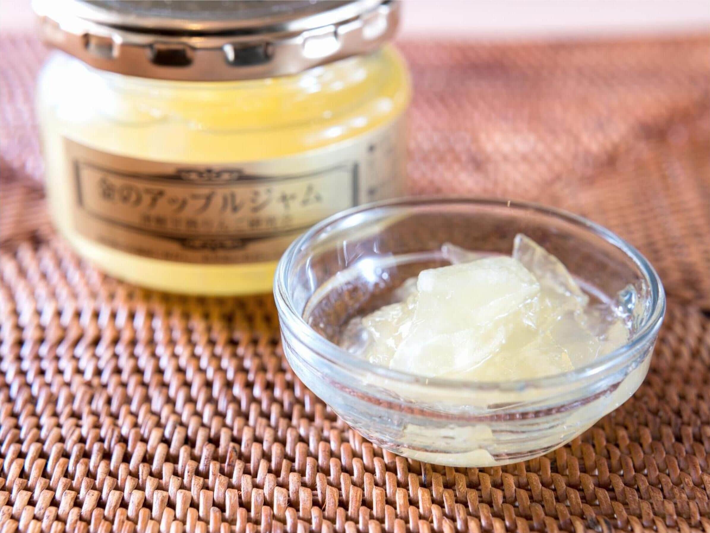A jar of honey and a small bowl with honey cubes on a woven mat.