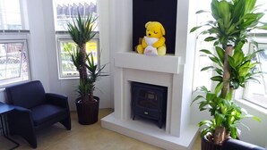A living room with a fireplace, a blue sofa, and two potted plants. - Family Lodge Hatagoya Meihan Nagashima (Kuwana)