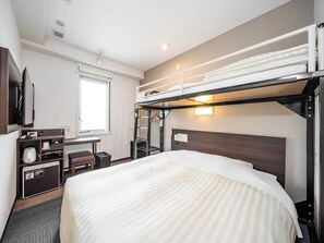 Habitación de hotel con literas, un escritorio con cafetera, televisión y ventana con persianas.
