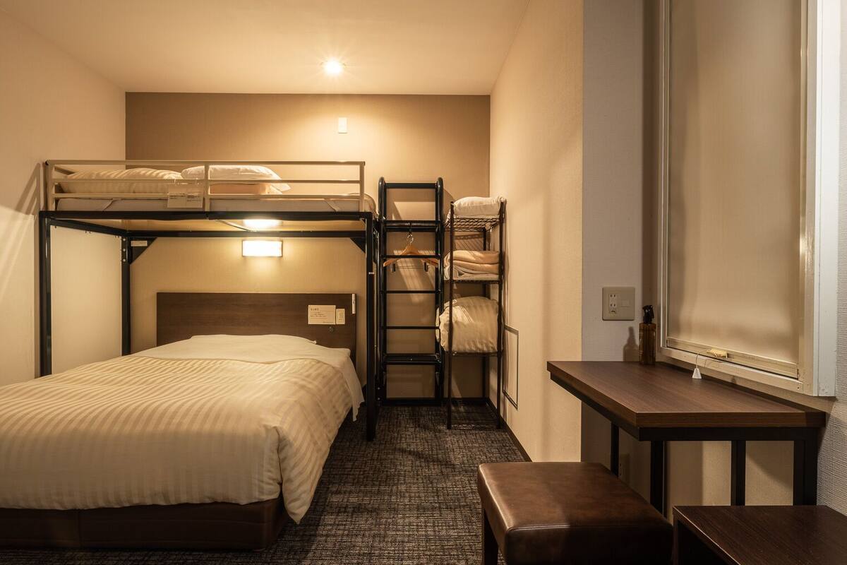 Habitació amb lliteres, una taula i una banca.
