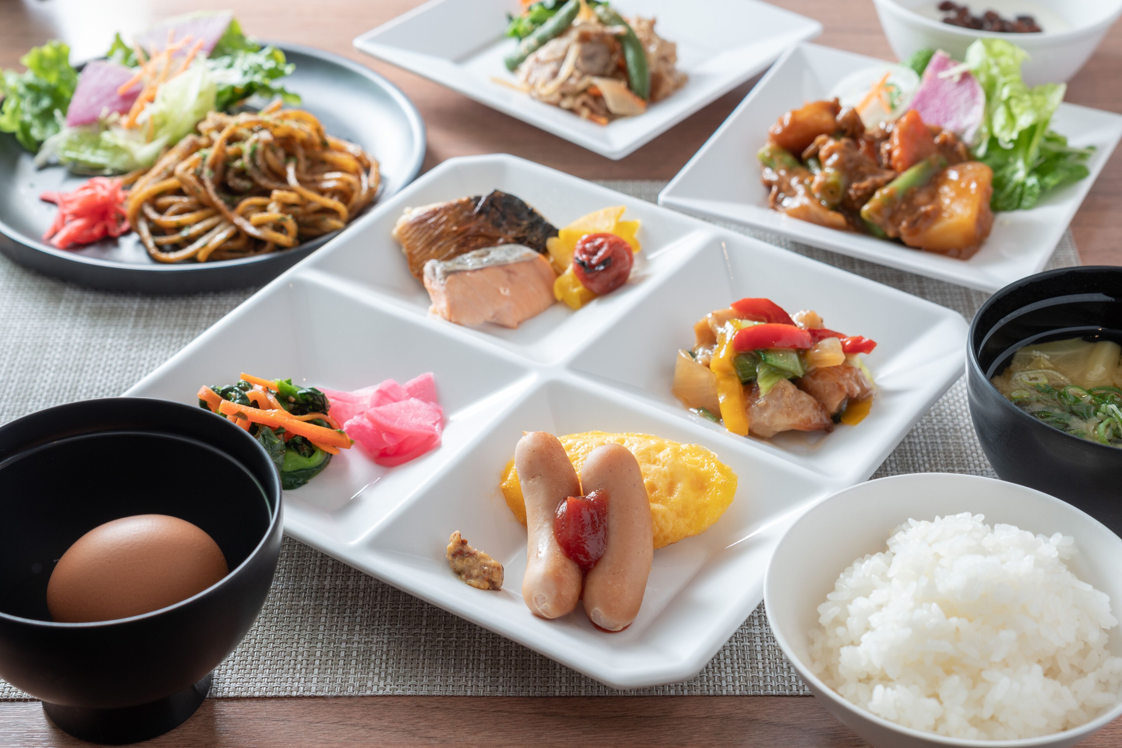 A variety of dishes on a table, including noodles, fish, and vegetables.