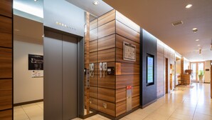 Un ascensor moderno con pantalla digital, paneles de madera y suelo de baldosas.