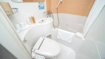 A compact bathroom with a toilet, sink, and shower.