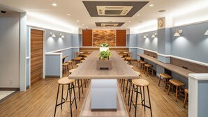 Un comedor moderno con una larga mesa de madera, diferentes opciones de asiento e iluminación empotrada en el techo.