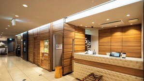 Un moderno vestíbulo de hotel con mostrador de recepción, paneles de madera y una zona de estar.