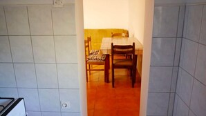 A dining area with a table and chairs, a yellow cushioned bench, and a tiled floor. - Cosy Apartment With sea View and one Bedroom (Novalja)