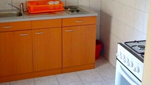 A kitchen with wooden cabinets, a sink, and a stove. - Cosy Apartment With sea View and one Bedroom (Novalja)