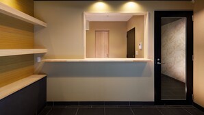 A reception area with a counter, a wooden door, and a patterned wall. - Connect Inn Gionshijo (Kyoto)