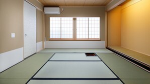 A traditional Japanese room with tatami flooring, sliding doors, and a window with a grid pattern. - Connect Inn Gionshijo (Kyoto)