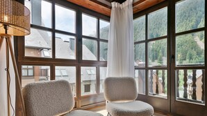 Una habitació amb grans finestres, dues butaques mullides i un sostre de fusta.