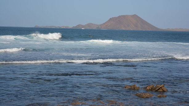 A coastal scene with waves, rocks, and distant mountains. - Lovely House Near to the sea (La Oliva)