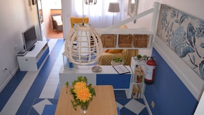 A modern living room with a sofa, a dining table with a vase of flowers, a television, and a bookshelf. - Lovely House Near to the sea (La Oliva)