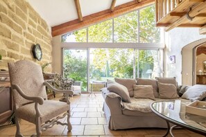 Ein geräumiges Wohnzimmer mit großem Fenster, bequemer Couch, Sessel und Glastisch.
