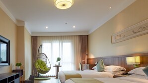 Una habitación de hotel con dos camas, un sillón colgante, un televisor y un cuadro en la pared.