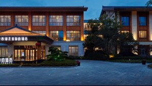 Un hotel de estilo arquitectónico tradicional, con una entrada grande de techo adoquinado y fachada bien iluminada.