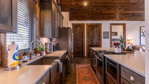 A modern kitchen with wooden cabinets, a large island, and a rustic ceiling. - Green Valley III at Eagles Nest, amazing views! (Banner Elk)