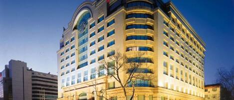 A multi-story hotel with a curved facade, large windows, and a prominent neon sign.