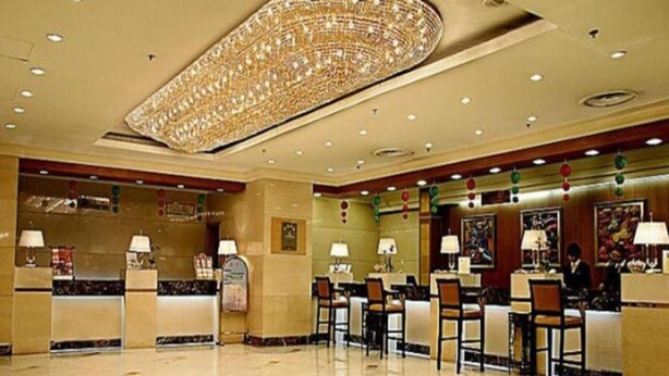 En hotellobby med en stor kristallkrona, receptionsdisk och flera stolar.