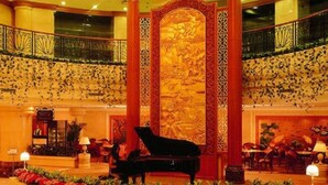 En storslagen entréhall med ett piano, utsmyckade kolonner och en dekorativ vägg.