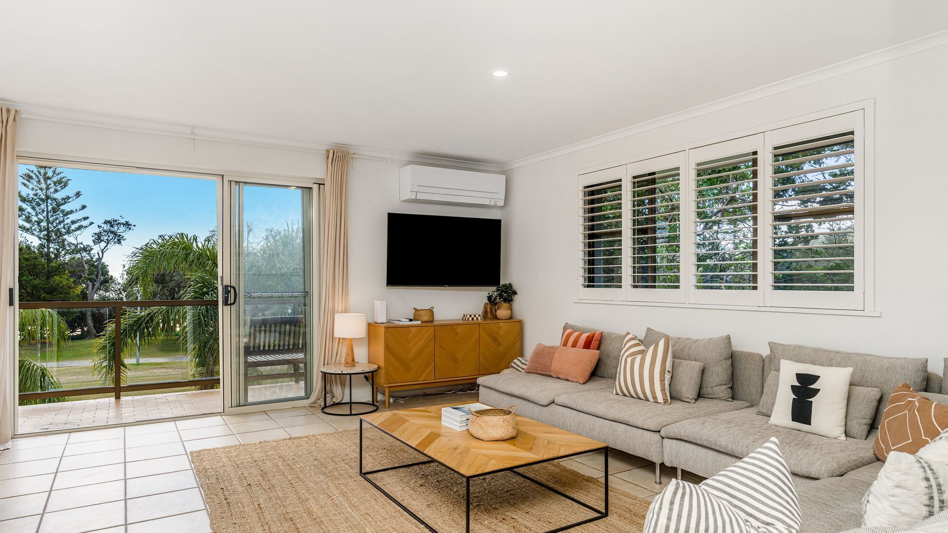A spacious living room with a sofa, coffee table, and a flat-screen TV.