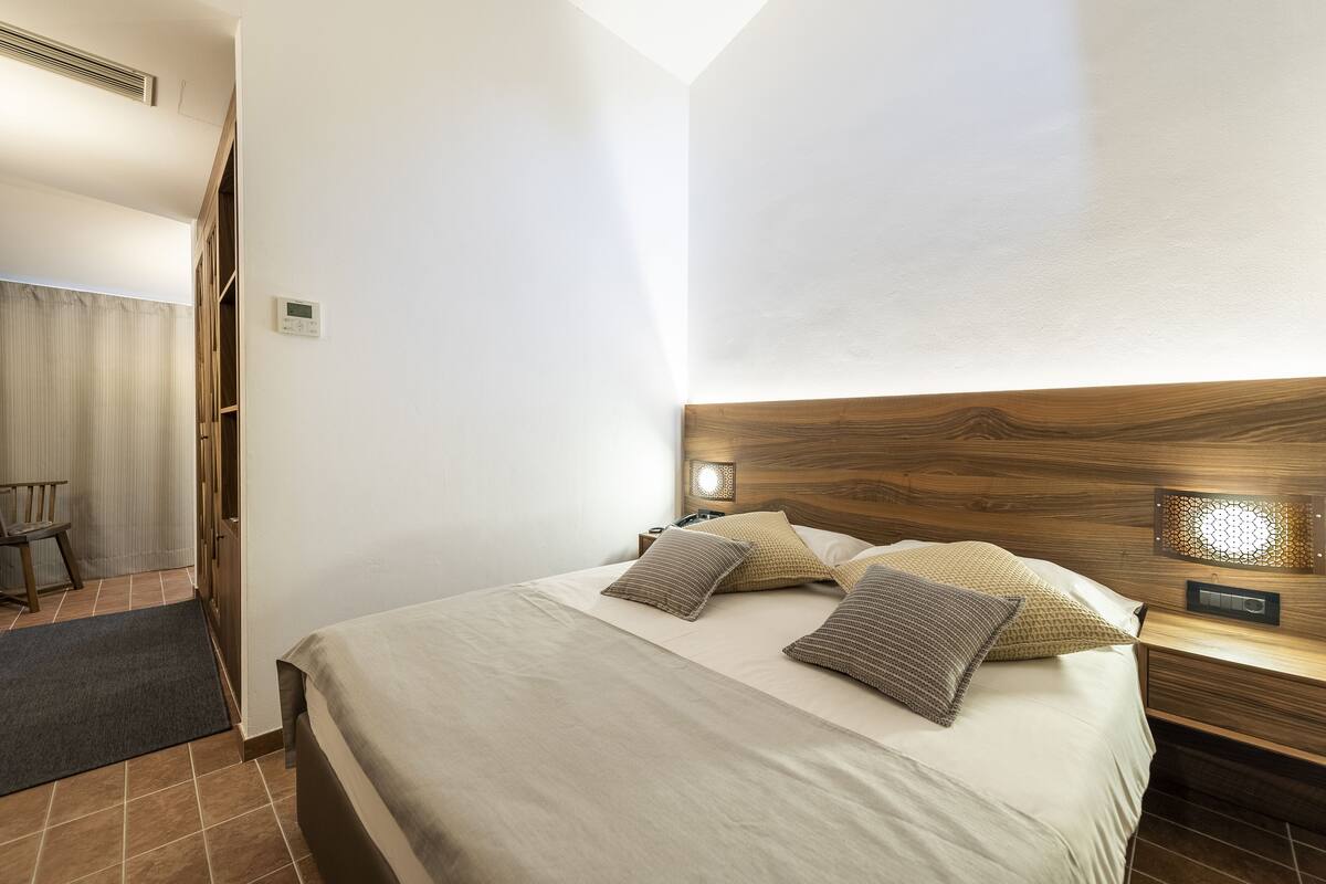 Een keurig opgemaakt slaapkamer met een bed, nachtkastjes en een nachtkastje.