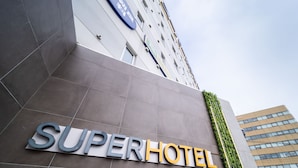 Une enseigne SuperHotel sur la façade d’un immeuble au design moderne, agrémentée d’un jardin vertical.
