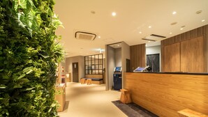 Un espace d’accueil moderne avec un comptoir en bois, des sièges et un mur végétal.