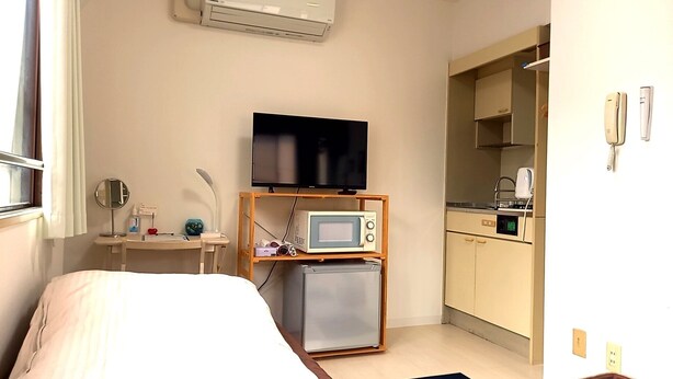 A compact hotel room with a bed, a TV, a small kitchenette, and a microwave. - Guest house Shijo K12 (Kyoto)