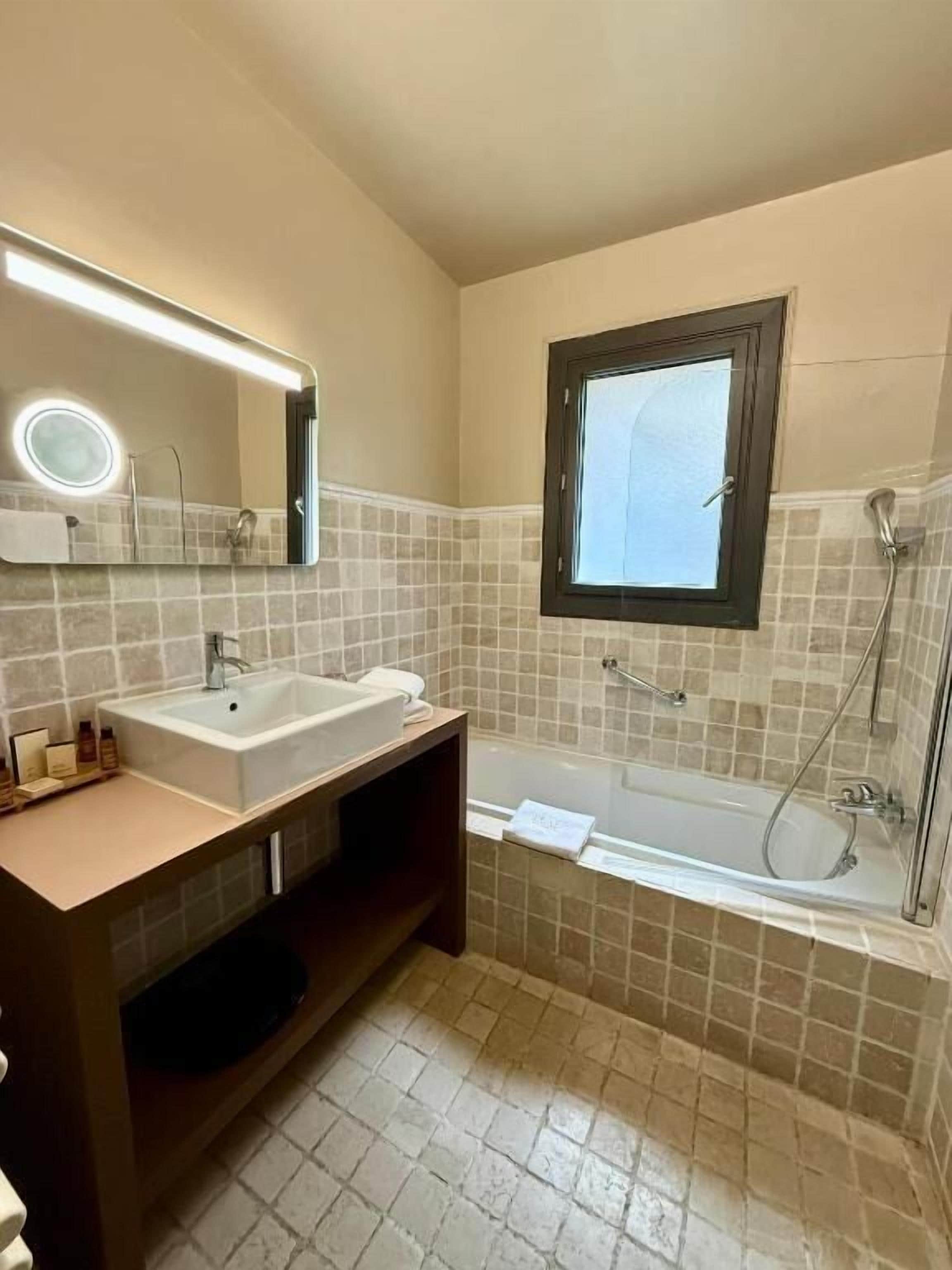Ein Badezimmer mit Waschbecken, Spiegel und Badewanne.
