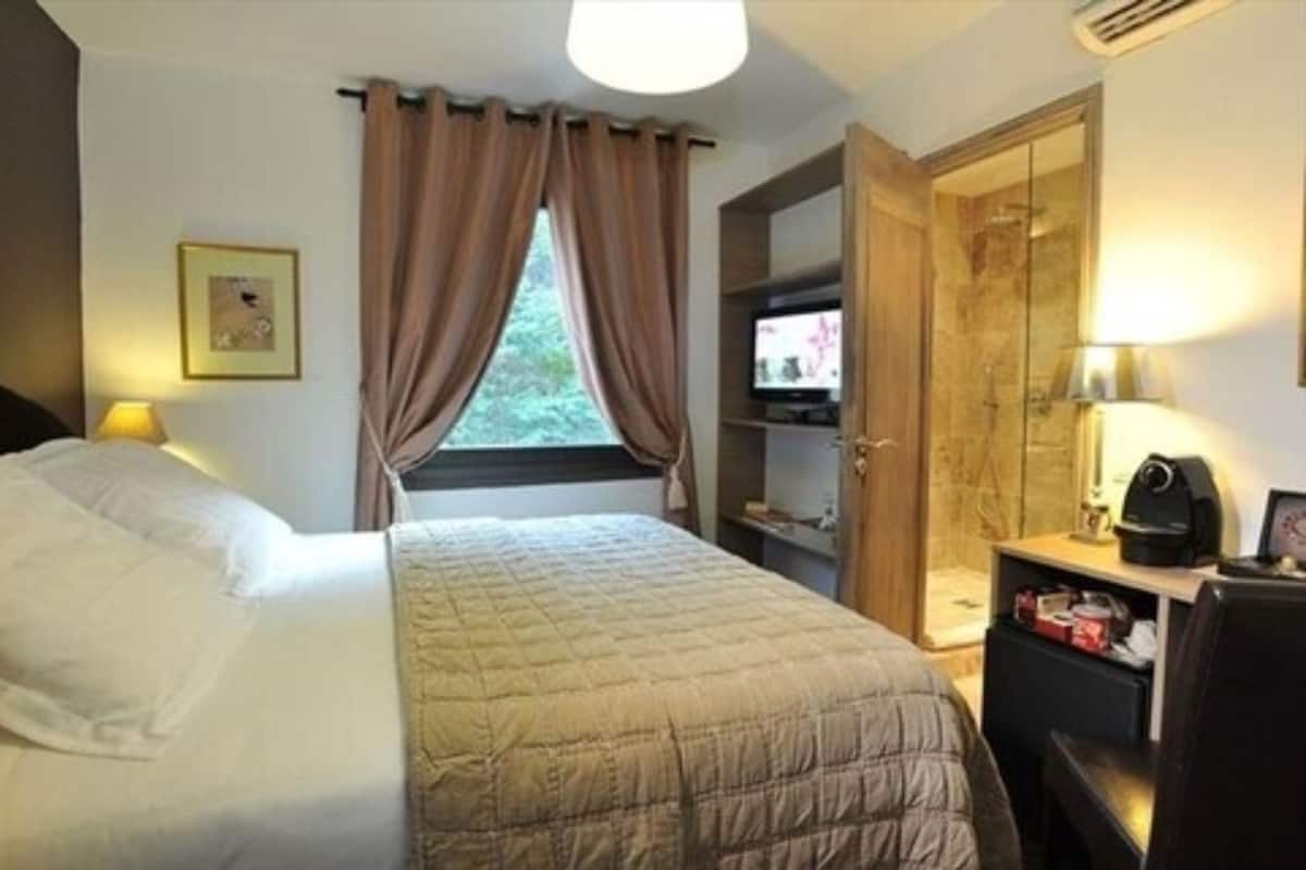 Une chambre d’hôtel comprenant un lit, un bureau avec une lampe, une télévision et une armoire.
