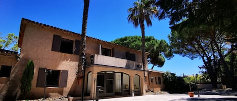 Un bâtiment à deux étages, doté d’un toit recouvert de tuiles, d’un balcon et d’une grande fenêtre.