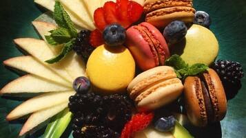 Une assiette de dessert avec divers fruits et des macarons.