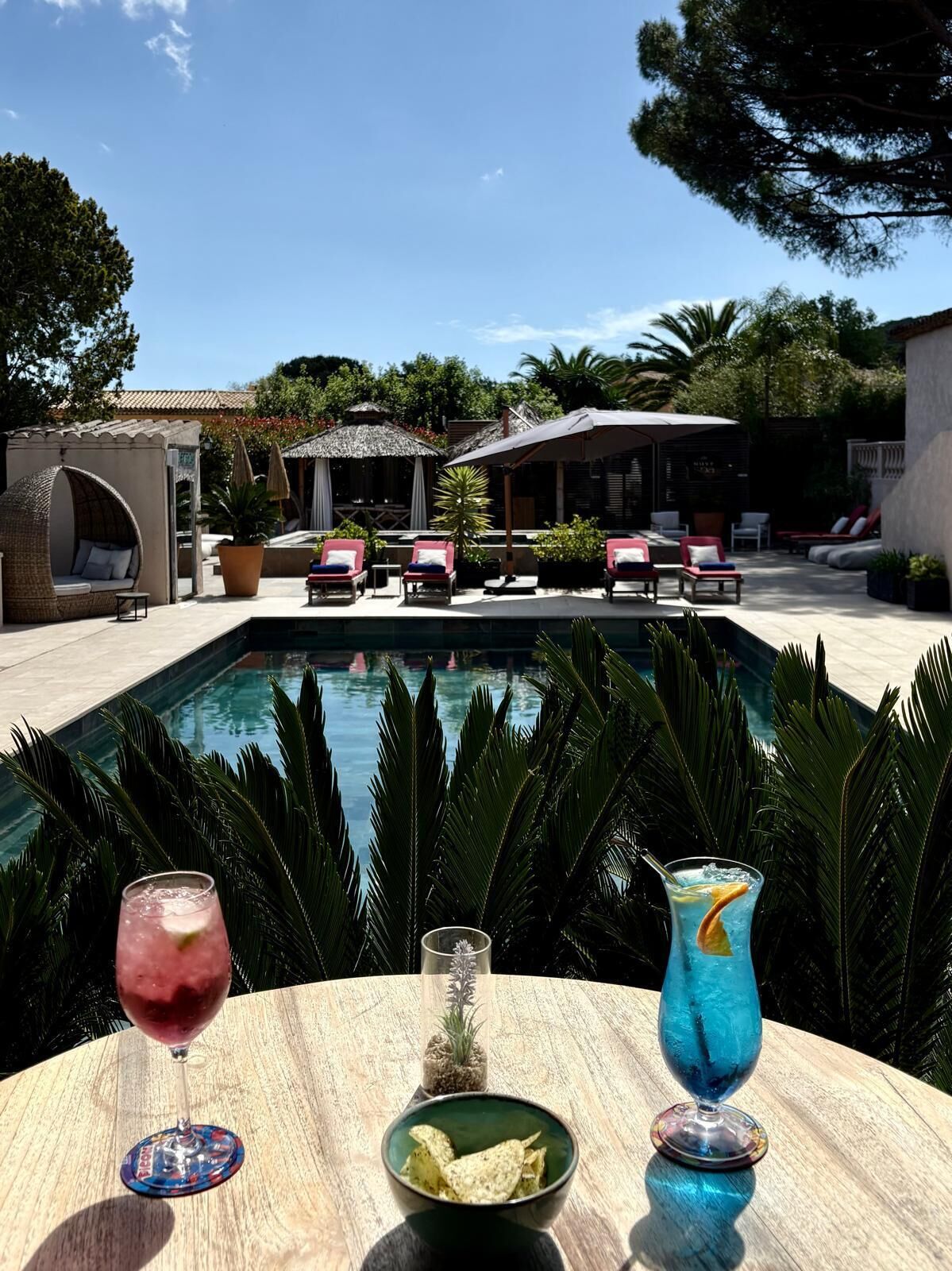 Ein Poolbereich mit Liegestühlen, einem Esstisch mit Getränken und Snacks sowie Blick auf den Pool.