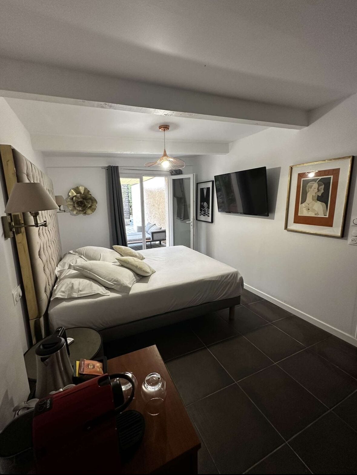 Une chambre à coucher avec un lit, un bureau avec une lampe, une télévision et un tableau encadré au mur.