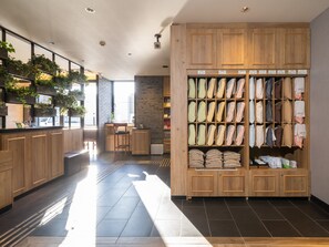 Un moderno vestíbulo de hotel con muebles de madera, una zona de estar y una exhibición de toallas y batas.