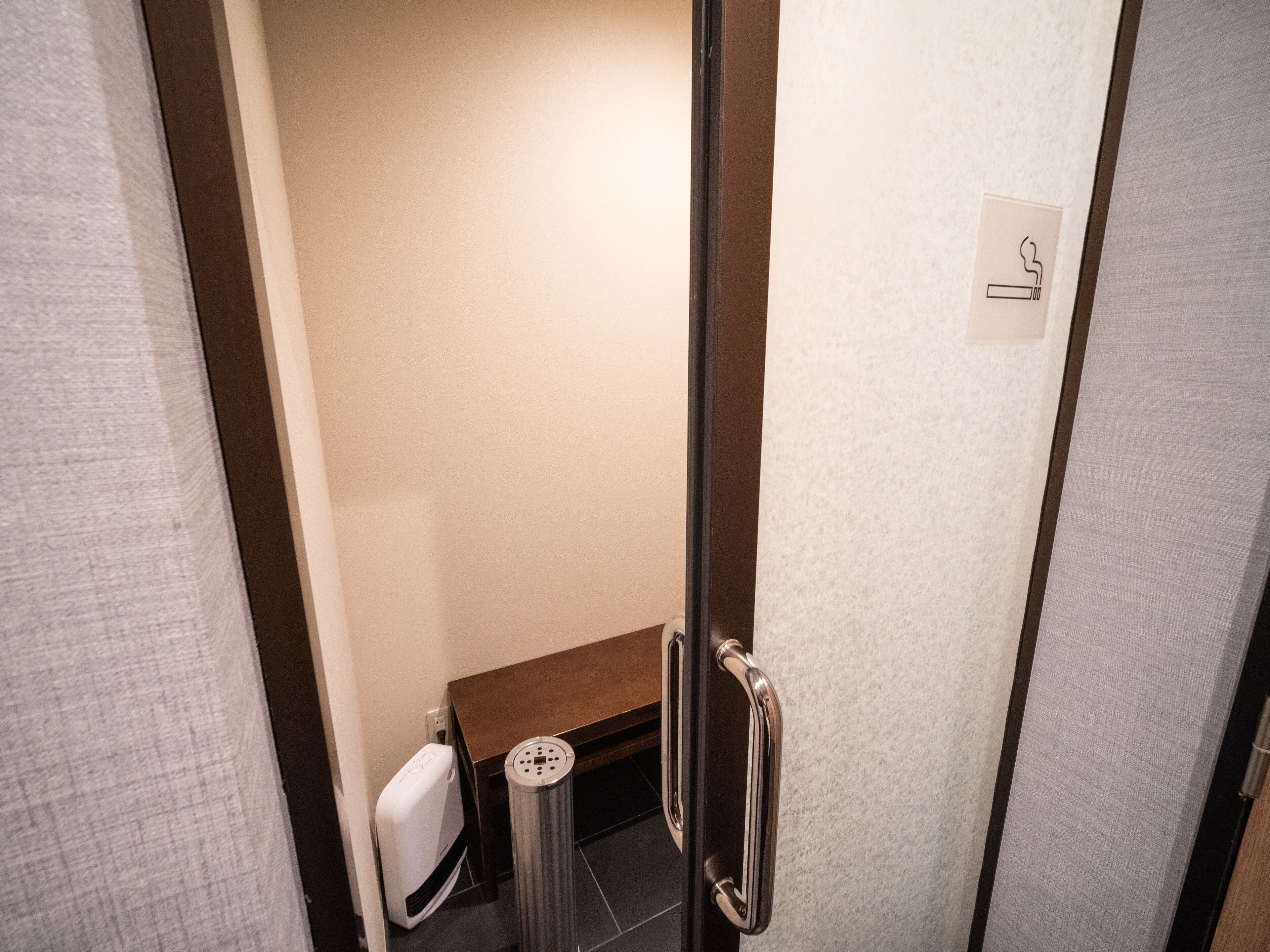 A hotel bathroom with a toilet, a trash bin, and a hand dryer.