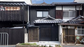 A traditional Japanese house with a dark wooden exterior, a tiled roof, and a bicycle parked outside.