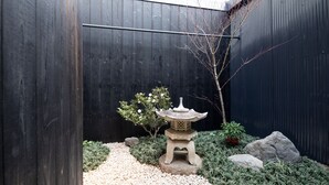 Un jardín con un farol de piedra, rocas y plantas.