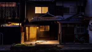 Una casa tradicional japonesa con un portón de madera, una bicicleta y un techo de tejas.