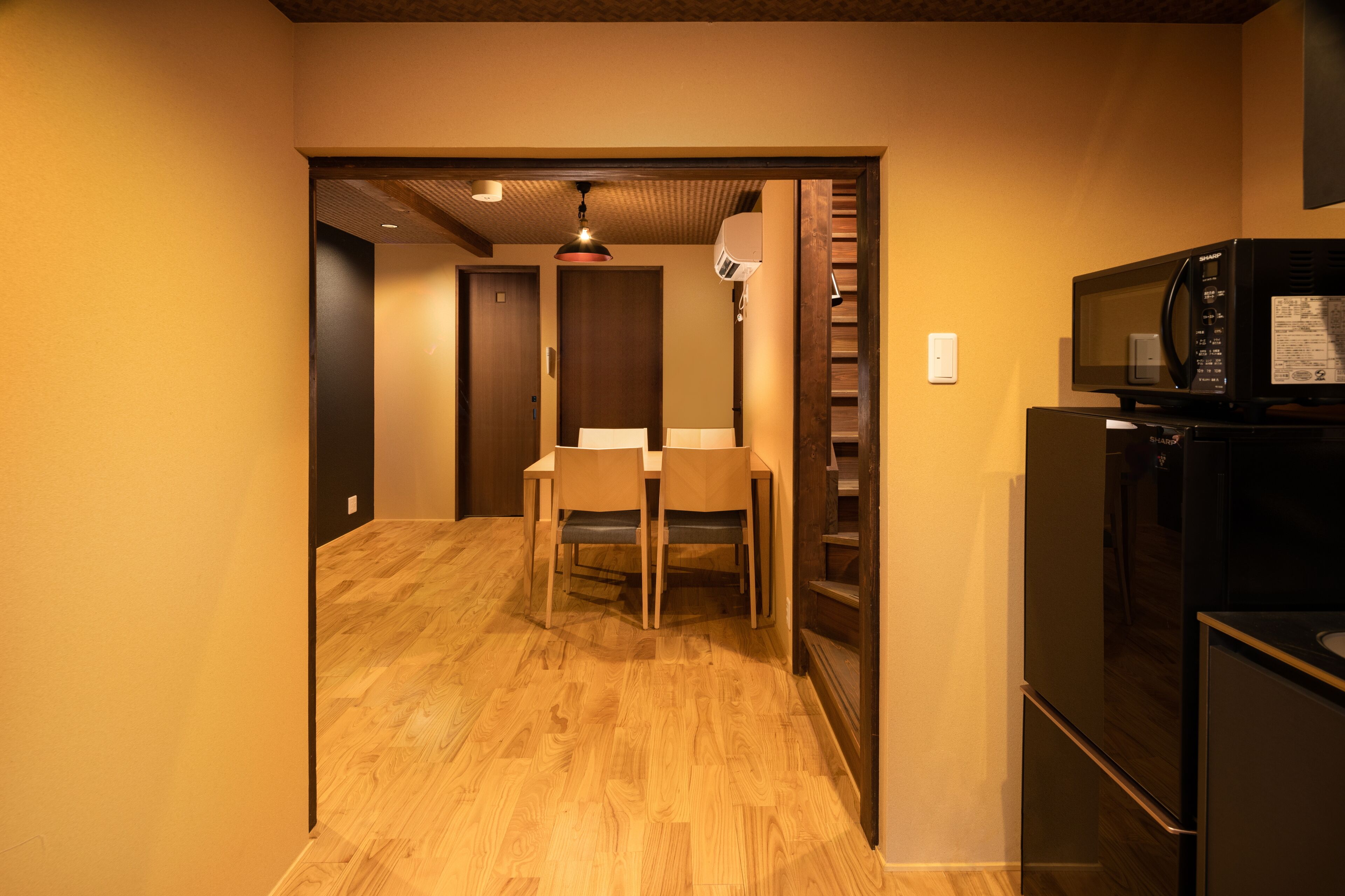 A compact kitchen with a microwave, refrigerator, and a dining area with chairs and a table.