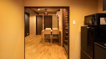 A compact kitchen with a microwave, refrigerator, and a dining area with chairs and a table.