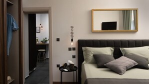 A bedroom with a bed, a bedside table, a mirror, and a view into the kitchen. - Luxury Sea View Apartment Altana (Pula)