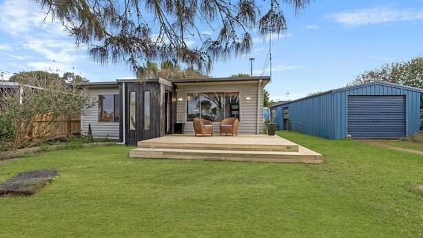 A modern house with a patio, two wicker chairs, and a blue garage. - Willan - 43 Powling Street (Port Fairy)