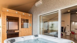 Ein modernes Badezimmer mit einer großen, freistehenden Badewanne, einer Holztür und einer Duschkabine aus Glas.