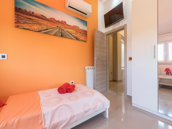 A bedroom with a bed, a painting, an air conditioner, a television, and a bathroom door. - Luxury Villa Maxima (Marcana)