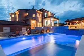 A modern house with a swimming pool, lounge chairs, and a well-lit exterior. - Luxury Villa Maxima (Marcana)